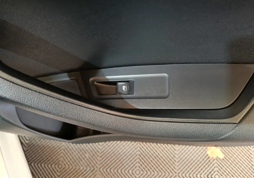 Détail de la commande d’ouverture de coffre sur la portière côté conducteur d’un Skoda Karoq blanc 2024.