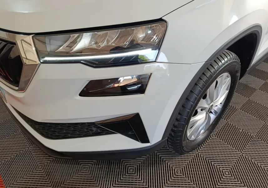 Gros plan sur l'avant droit blanc du Skoda Karoq 2024, mettant en valeur le phare LED et la roue alliage.