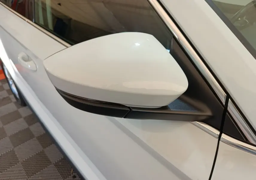 Rétroviseur blanc côté conducteur du Skoda Karoq 2024, avec carrosserie blanche et détails noirs brillants.