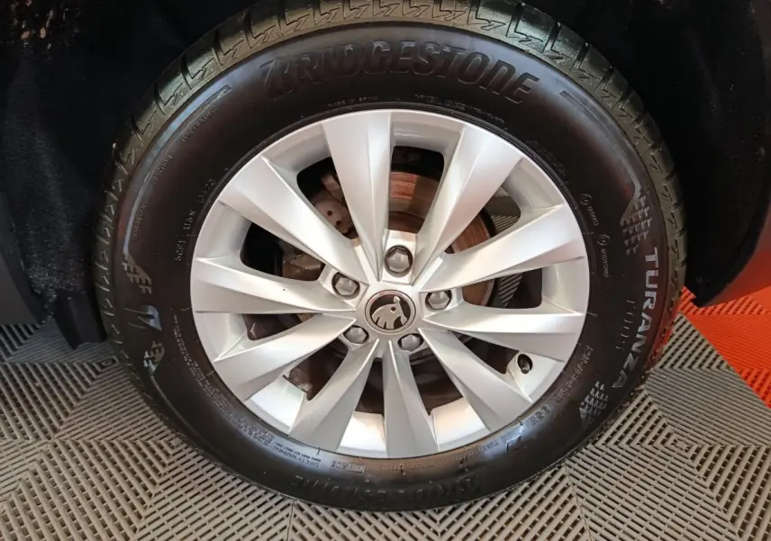 Gros plan sur la roue avant droite d’un Skoda Karoq blanc avec jante alliage et pneu Bridgestone Turanza.