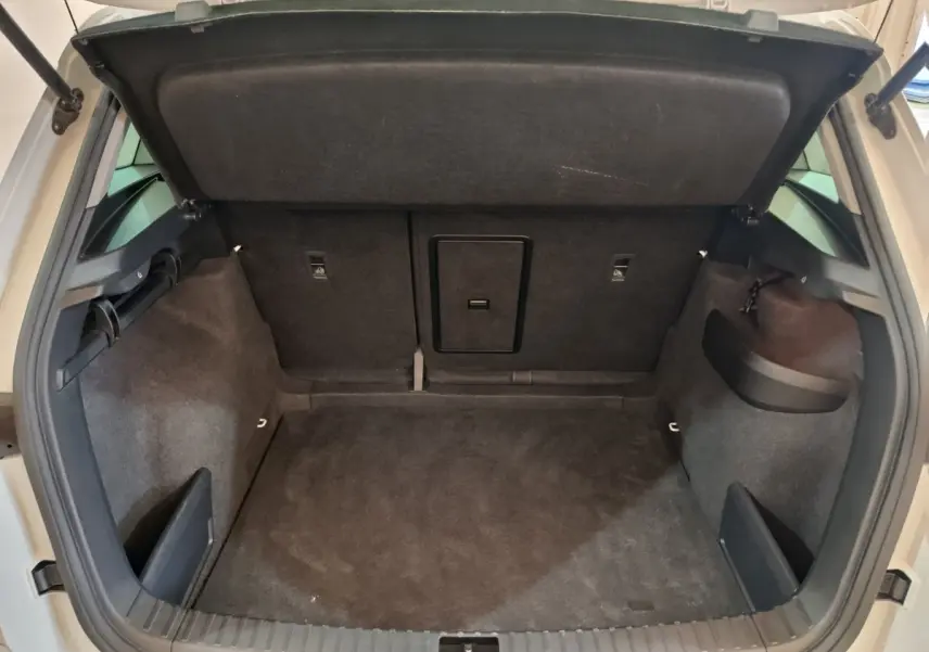 Coffre ouvert vu de l'arrière d'un Skoda Karoq blanc 2024, espace de chargement propre et vide avec habillage noir.