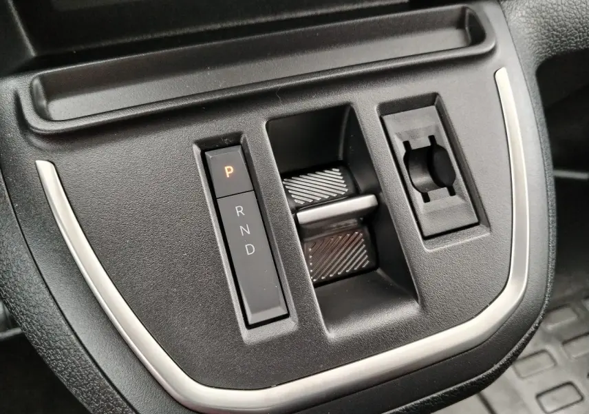 Gros plan sur la console centrale noire du Peugeot Expert M 2.0 BlueHDi 180, avec commandes de boîte auto et finition argentée.