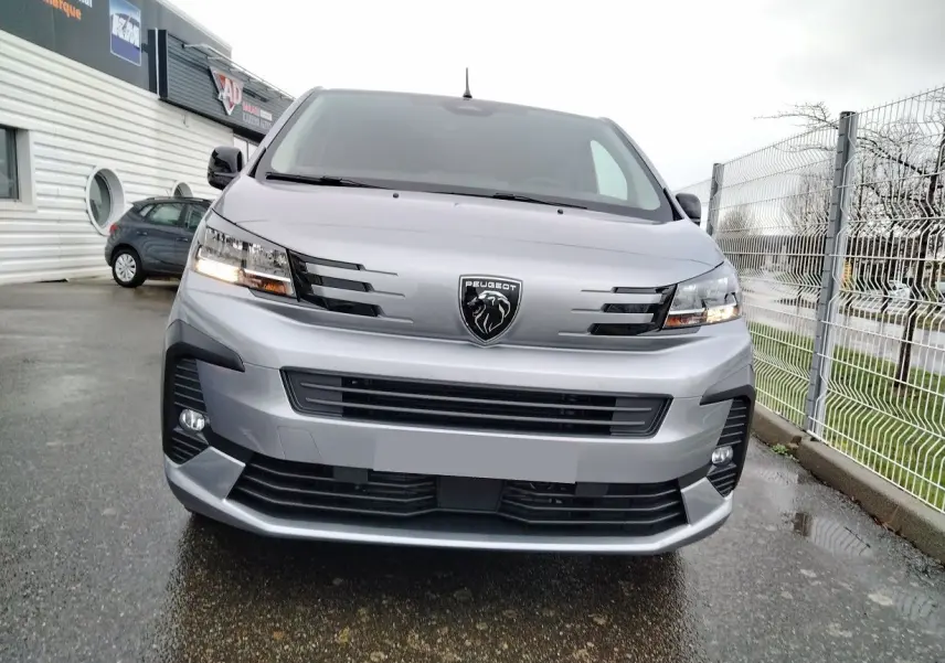 Vue frontale d'un Peugeot Expert Cabine Approfondie gris Artense avec calandre moderne et phares allumés.