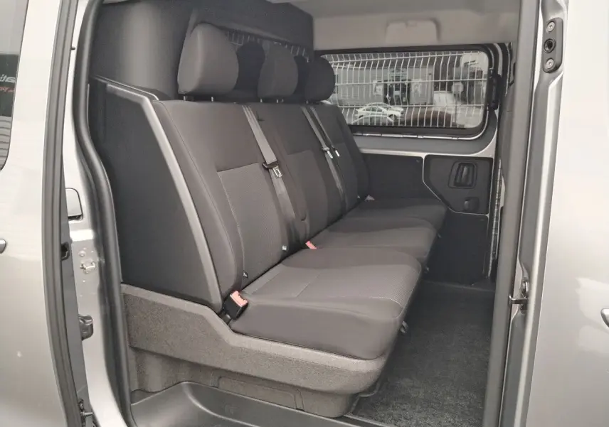 Vue intérieure côté gauche du Peugeot Expert cabine approfondie 2025 gris Artense, montrant la banquette arrière 3 places avec ceintures et séparation grillagée.