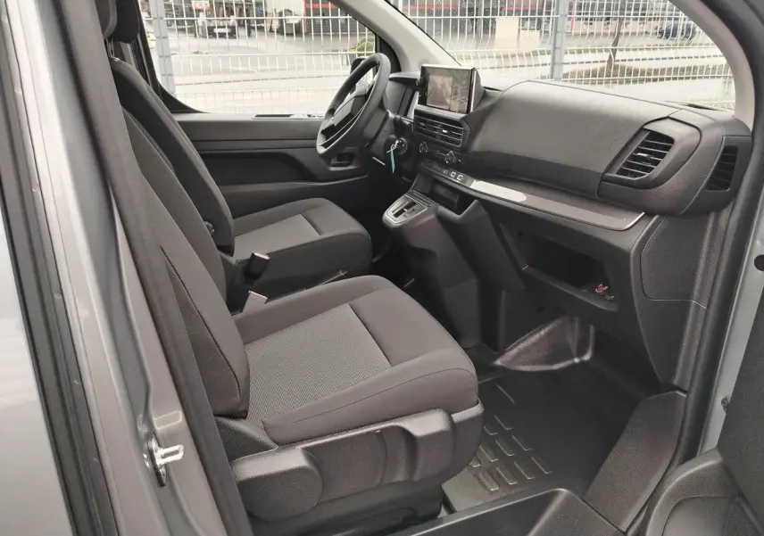 Vue intérieure côté conducteur du Peugeot Expert gris Artense, montrant les sièges tissu et le tableau de bord moderne avec écran central.