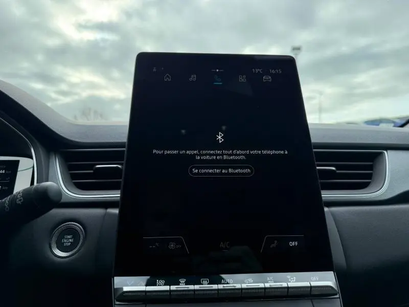 Intérieur du Renault Captur 2025, vue centrée sur l'écran tactile noir brillant et la console centrale, avec bouton démarrage visible.