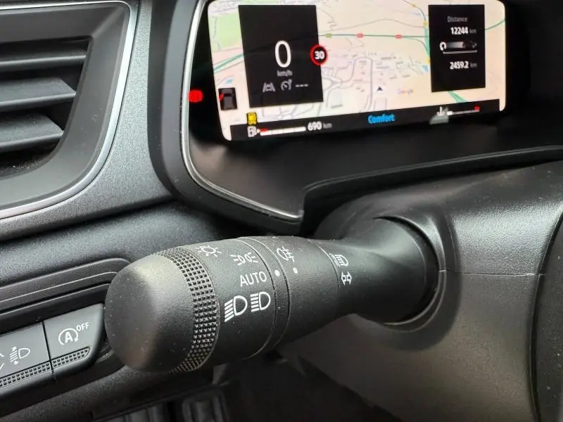 Gros plan sur la commande des phares à gauche du volant dans le Renault Captur 2025, avec écran numérique en arrière-plan.
