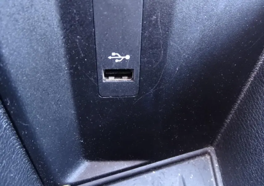 Gros plan sur le port USB intégré dans la console centrale noire d'un BMW X1 blanc.