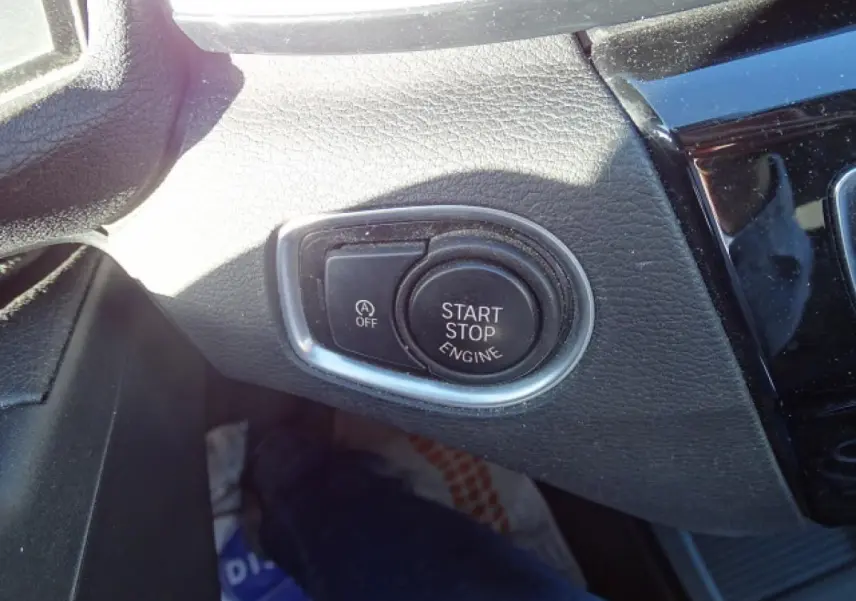 Gros plan sur le bouton Start/Stop moteur entouré de chrome dans l’habitacle noir du BMW X1 blanc 2017.