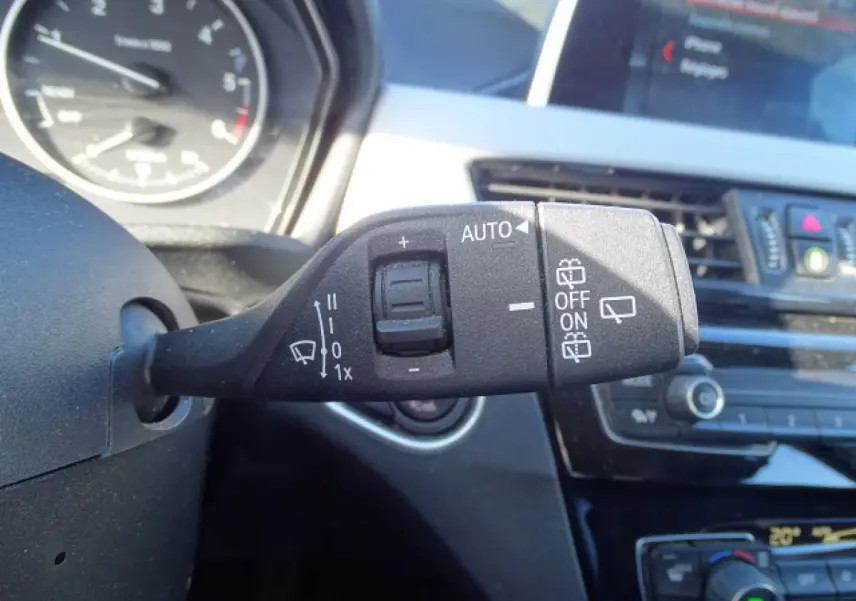 Gros plan sur la commande d’essuie-glace à gauche du volant dans l’habitacle d’un BMW X1 blanc de 2017.