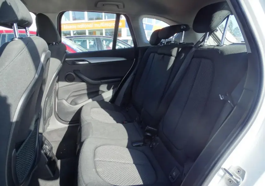 Vue intérieure côté droit des sièges arrière en tissu noir d'une BMW X1 blanc 2017, avec appuis-tête ajustables.