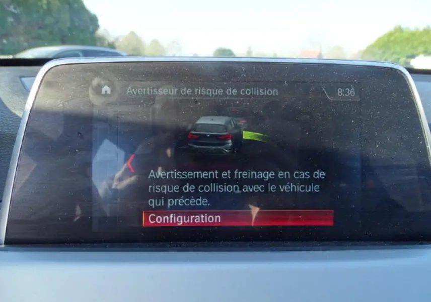 Écran central du BMW X1 blanc 2017 montrant l'alerte de risque de collision avec configuration en cours.