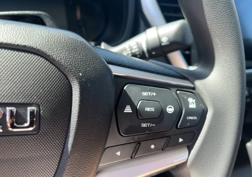 Gros plan sur le volant multifonctions noir de l'Isuzu D-MAX 2026 avec commandes de régulateur et assistance.