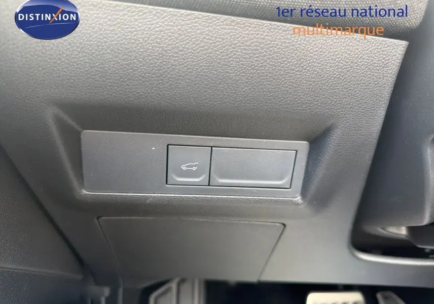 Bouton d'ouverture du coffre sur panneau noir sous le tableau de bord d'une Renault Symbioz gris cassiopée.