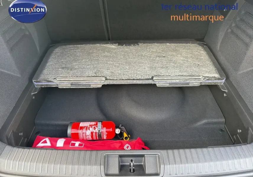 Coffre ouvert d’une Renault Symbioz gris cassiopée, montrant un extincteur rouge et une trousse de secours rouge.