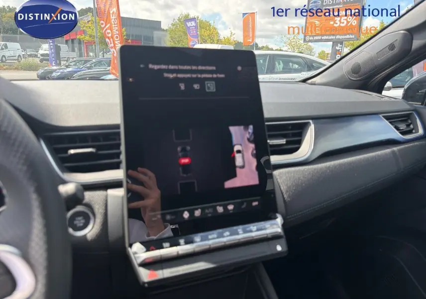 Vue intérieure du tableau de bord de la Renault Symbioz gris cassiopée, avec écran tactile central affichant la caméra 360° et détails du volant partiel.