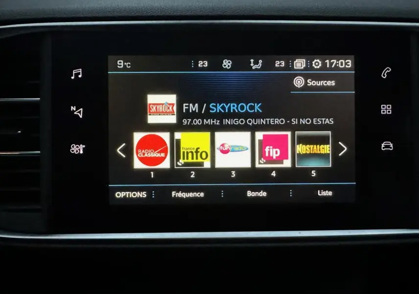 Écran tactile central du tableau de bord du Peugeot 308 gris Artense affichant les stations radio FM.