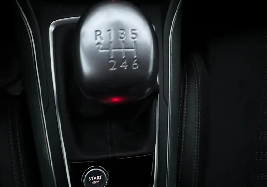 Gros plan sur le levier de vitesses manuel et le bouton start/stop dans l'habitacle noir d'une Peugeot 308.