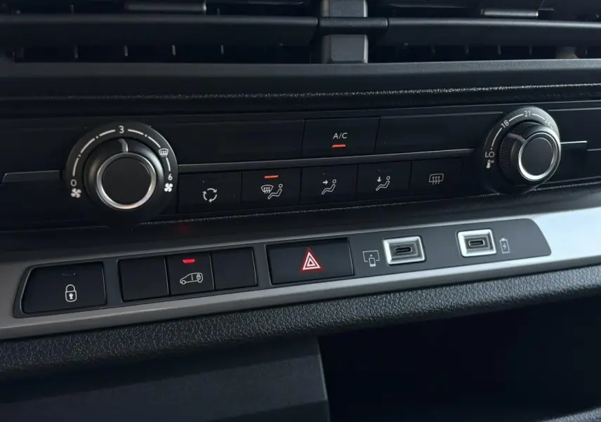 Vue rapprochée du tableau de bord du Citroën Jumpy gris, montrant les commandes de climatisation et boutons centraux.