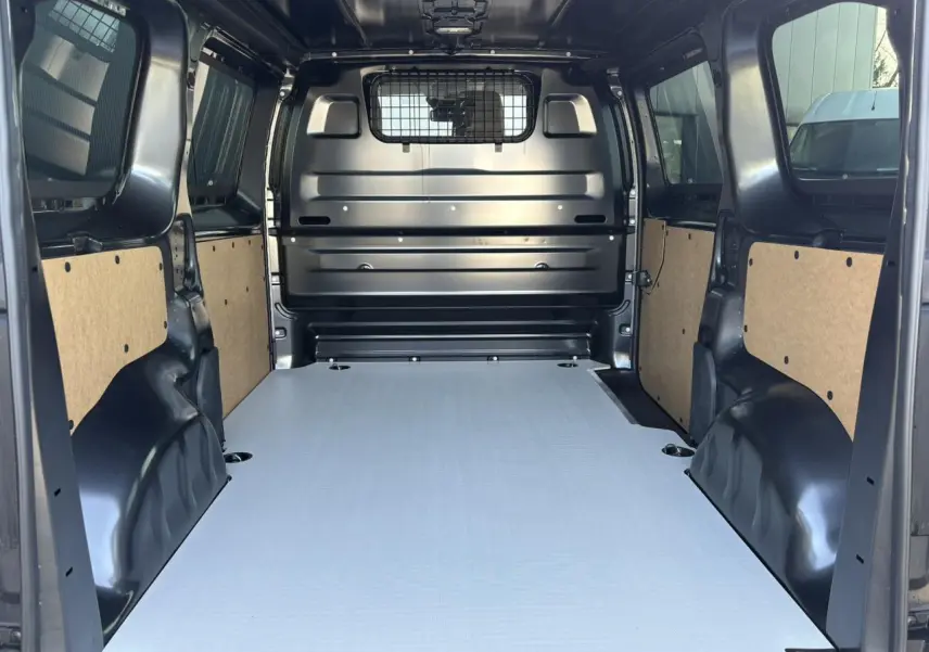 Vue intérieure arrière du Citroën Jumpy gris Titane, montrant le plancher bois antidérapant et la cloison pleine vitrée isolante.