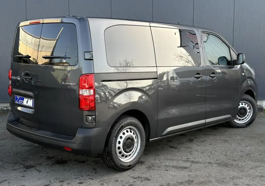 Vue 3/4 arrière droit d'un Citroën Jumpy gris titane avec portes arrière vitrées et jantes acier.