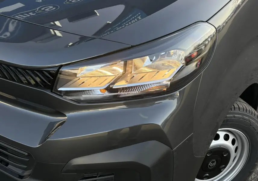Gros plan sur l’avant droit gris titane du Citroën Jumpy 2025, mettant en valeur le phare allumé et la roue acier.