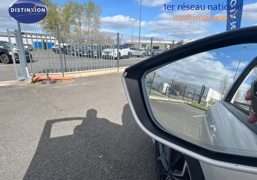 Rétroviseur côté droit reflétant la carrosserie blanche nacrée d'une DS4 2024, avec une roue alliage visible.