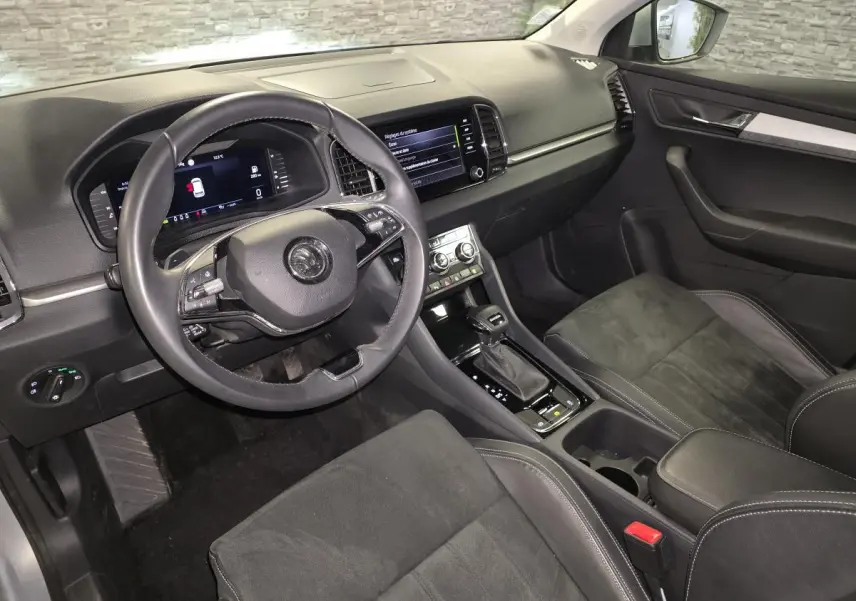 Intérieur avant droit du Skoda Karoq 2023 gris, volant cuir multifonction et console centrale avec écran tactile.