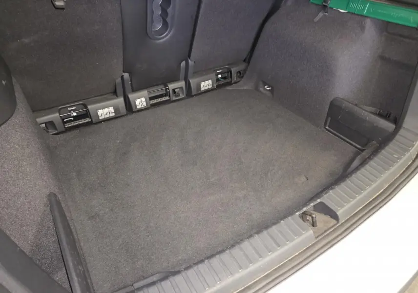 Vue intérieure du coffre spacieux et propre du Skoda Karoq gris, montrant les fixations ISOFIX arrière et les finitions en tissu noir.