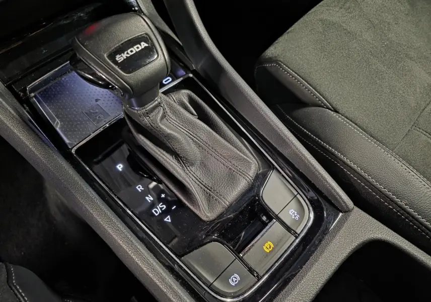 Gros plan sur le levier de vitesse en cuir noir et le chargeur à induction dans la console centrale du Skoda Karoq 2023.