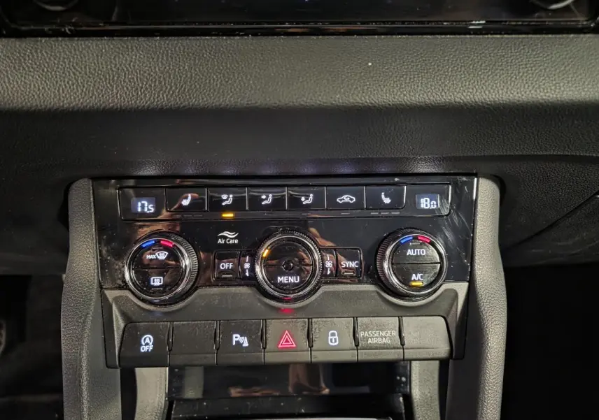 Gros plan sur la console centrale noire du Skoda Karoq 2023 avec commandes climatisation et boutons fonctionnels.