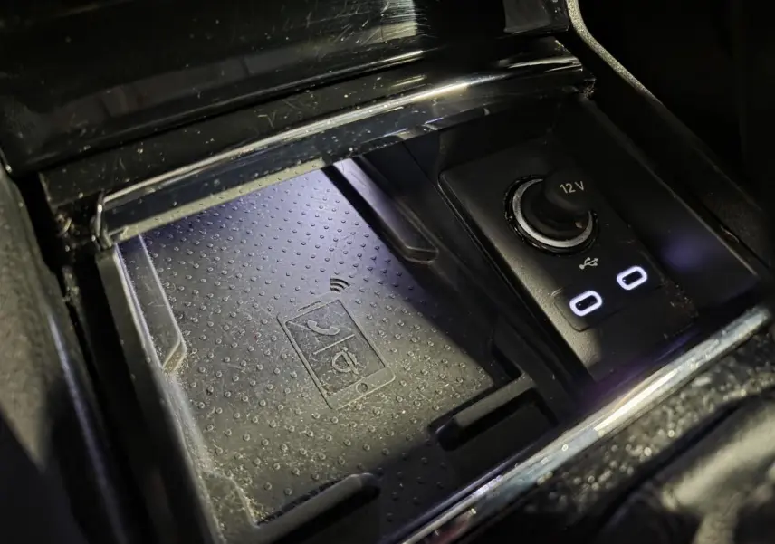 Gros plan sur le chargeur à induction et prises USB-C éclairées dans la console centrale du Skoda Karoq gris 2023.