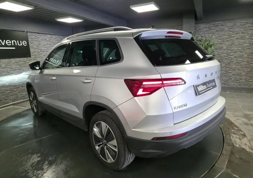 Vue 3/4 arrière droite d'un Skoda Karoq gris 2023 avec feux arrière LED et jantes alliage 17 pouces.