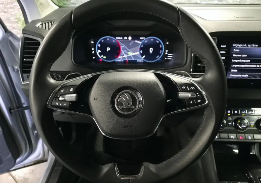 Vue rapprochée du volant cuir noir du Skoda Karoq 2023 avec tableau de bord numérique et écran tactile latéral.
