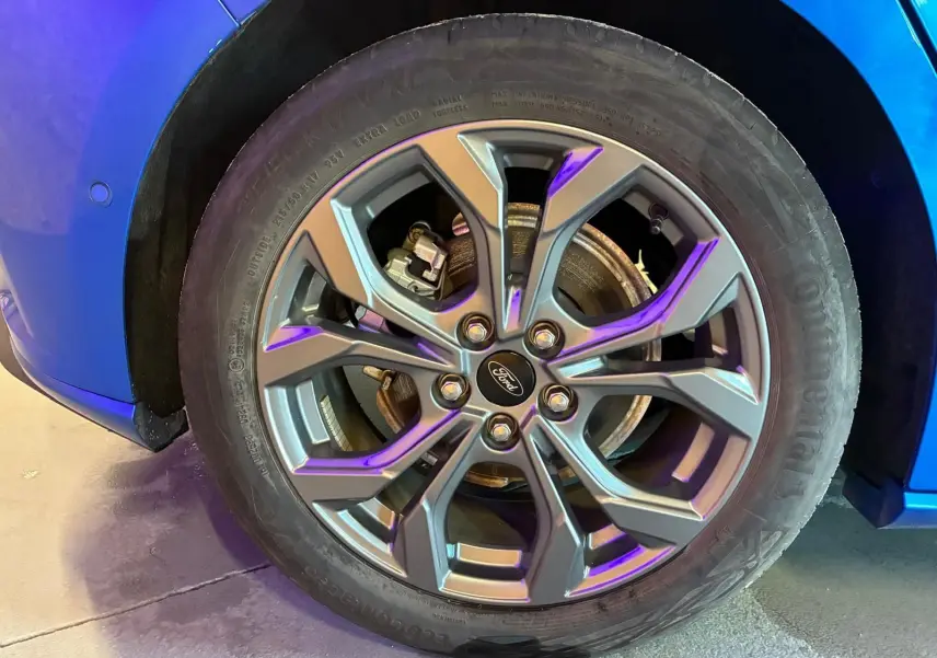 Gros plan sur la roue avant gauche de la Ford Focus 2024 bleu, avec jante alliage au design moderne et logo Ford central.