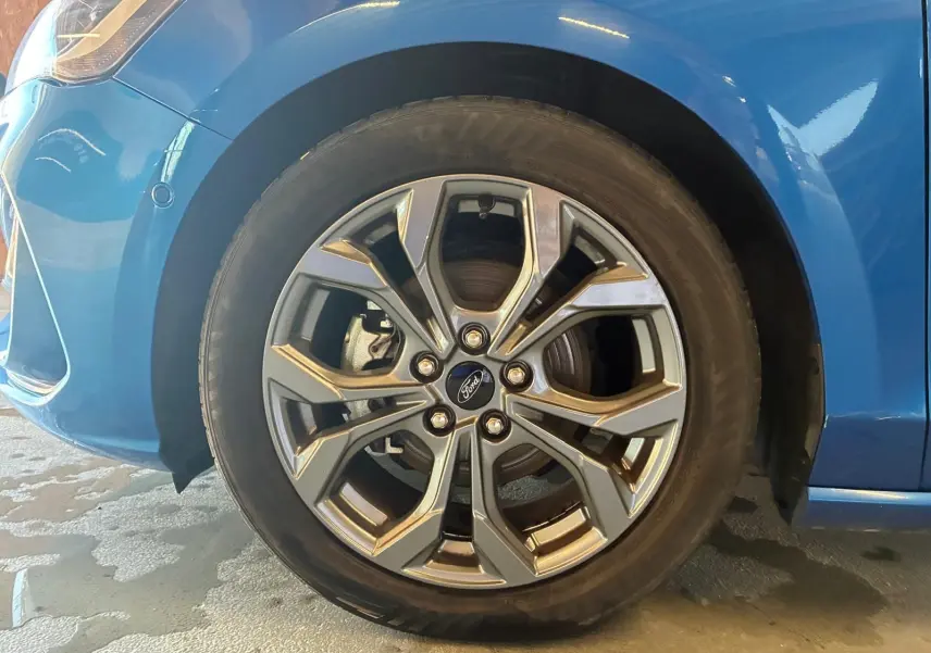 Gros plan sur la roue avant gauche de la Ford Focus bleue 2024 avec jante alliage au design moderne.