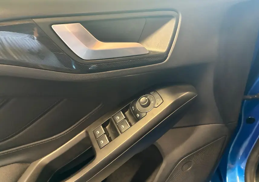 Détail de la porte avant gauche d’une Ford Focus bleue 2024, montrant les commandes des vitres et le revêtement intérieur noir.