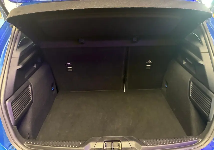 Coffre ouvert de la Ford Focus 2024 bleu, vue arrière montrant l’espace de chargement et les finitions intérieures noires.