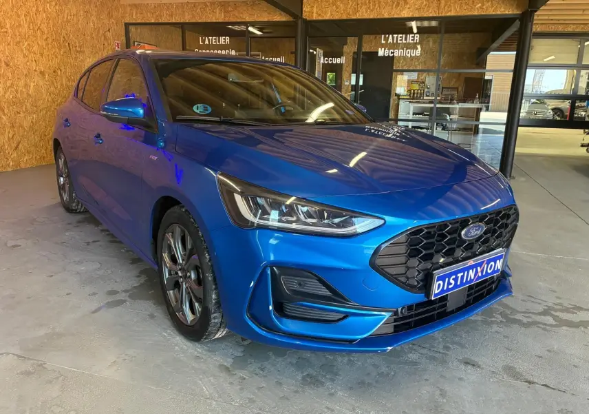 Ford Focus 1.0 EcoBoost hybride bleu en 3/4 avant droit, avec calandre noire et phares LED distinctifs.