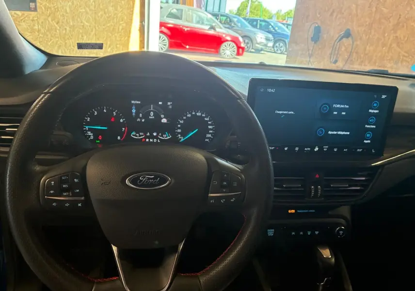 Vue intérieure centrée sur le volant Ford et le tableau de bord numérique d'une Ford Focus bleu 2024.