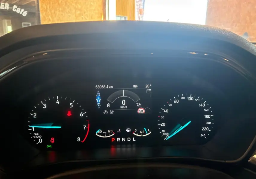 Tableau de bord numérique de Ford Focus bleu 2024, affichant vitesse à 0 km/h et indicateurs de température et carburant.