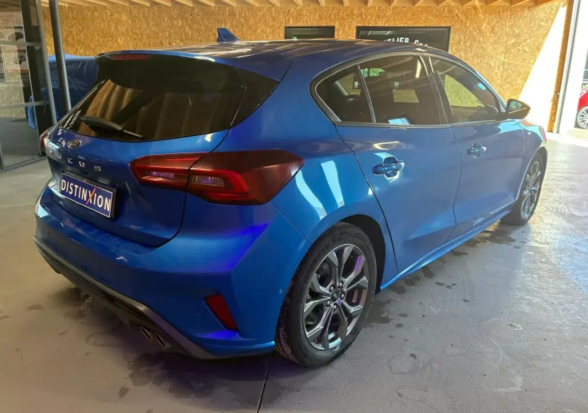 Vue 3/4 arrière droite d'une Ford Focus bleue 5 portes avec feux arrière LED et jantes alliage.