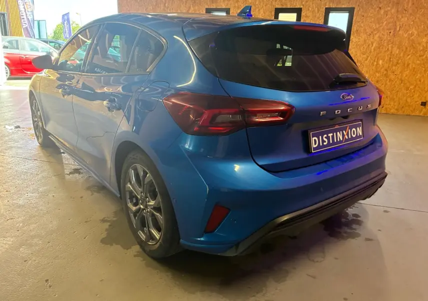 Vue 3/4 arrière droite d'une Ford Focus bleu 2024 ST Line avec feux LED et toit avec antenne requin.