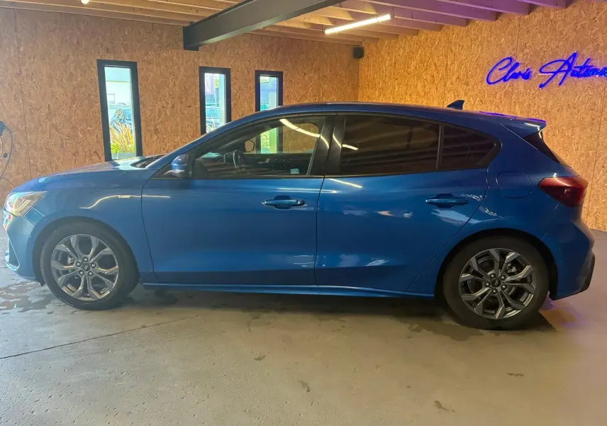 Vue de profil côté gauche d'une Ford Focus bleu 2024 en finition ST Line, avec jantes alliage et vitres teintées.