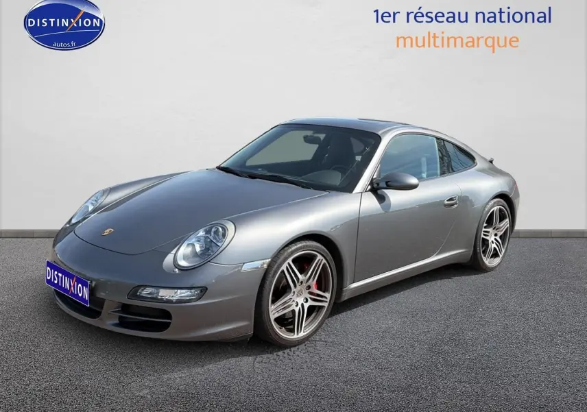 Porsche 911 (997) Carrera S gris vue 3/4 avant droit, avec jantes alu et phares bi-xénon visibles.