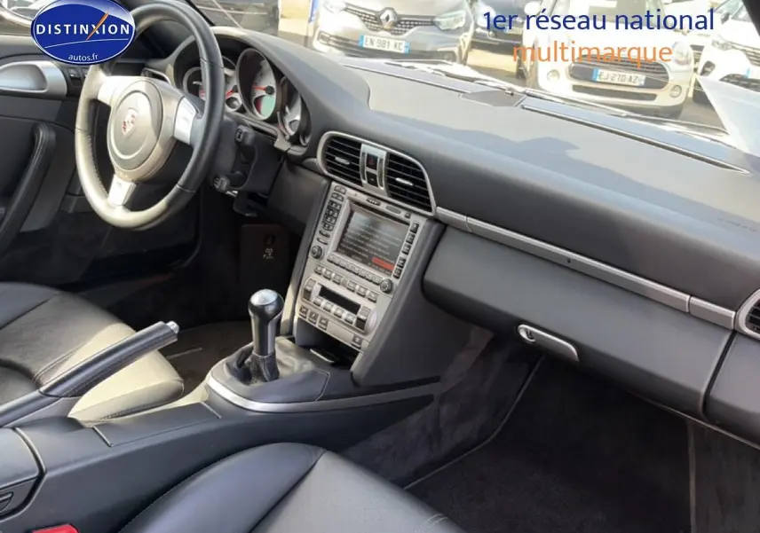 Intérieur de Porsche 911 (997) Carrera S 2008 vu côté passager, montrant tableau de bord et boîte manuelle cuir noir.