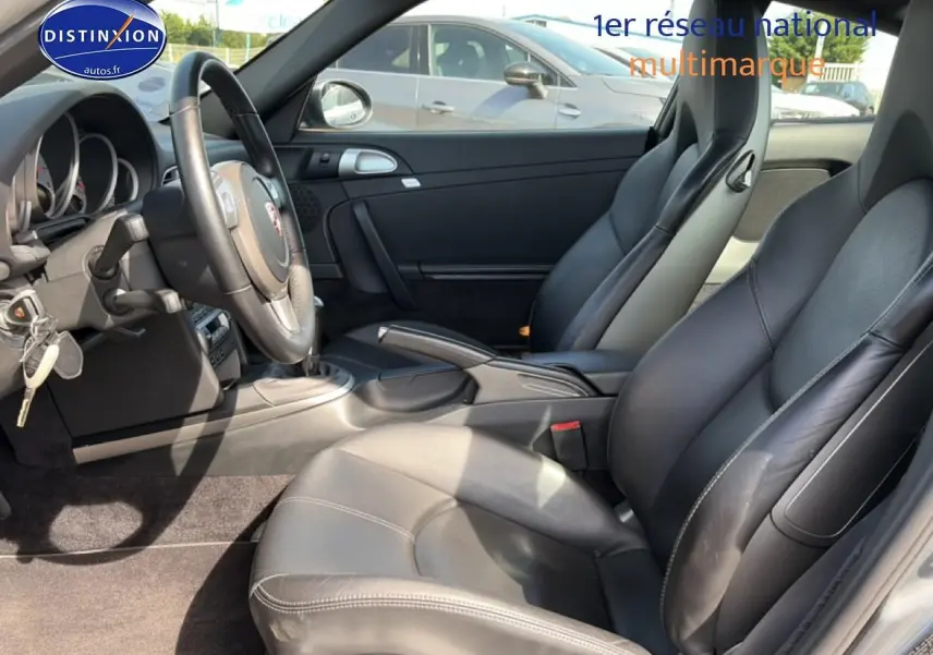 Vue intérieure côté conducteur de la Porsche 911 (997) Carrera S 2008 avec sellerie cuir noire et boîte manuelle.