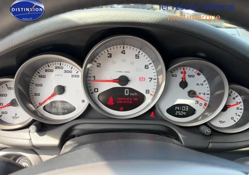 Vue rapprochée du tableau de bord de la Porsche 911 (997) Carrera S, avec compteurs blancs et affichage digital.