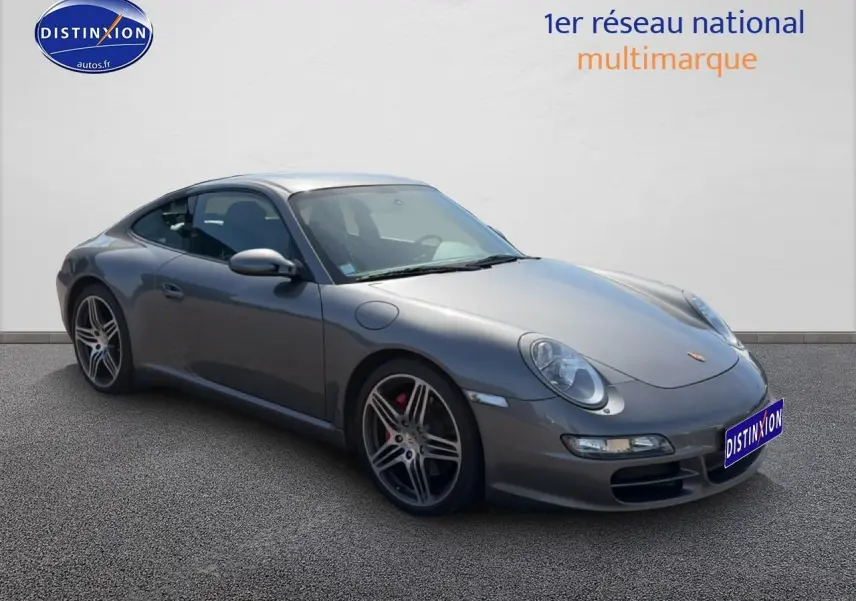 Porsche 911 (997) Carrera S gris vue 3/4 avant droit, jantes alu et phares bi-xénon visibles.