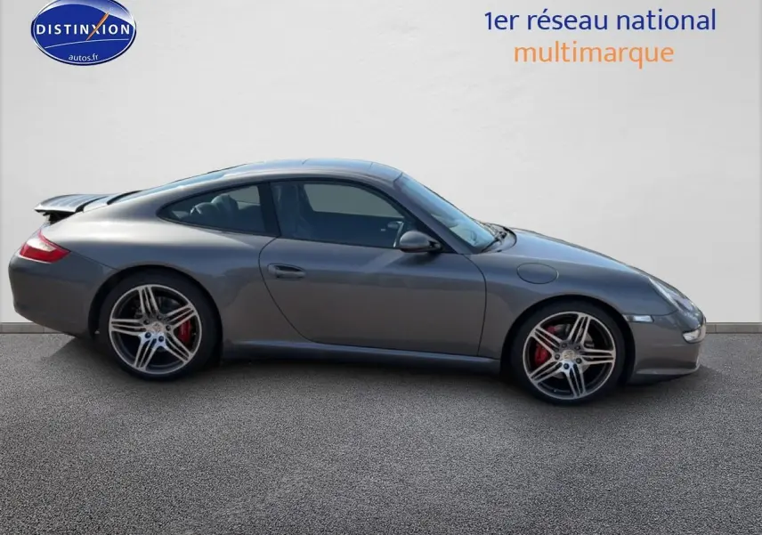 Profil droit d'une Porsche 911 (997) Carrera S gris métallisé avec jantes alu et aileron arrière déployé.